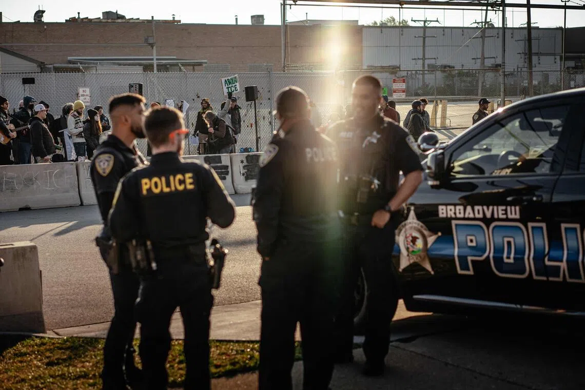 A group of local police officers watching demonstrators gather and sing in the "free speech zone" outside the ICE processing and detention facility in Broadview on Oct 31.