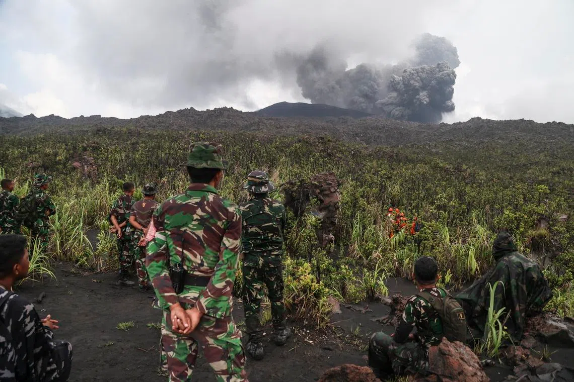 Rescuers look on Mount Dukono volcano during its eruption in North Halmahera, Indonesia, on May 9.