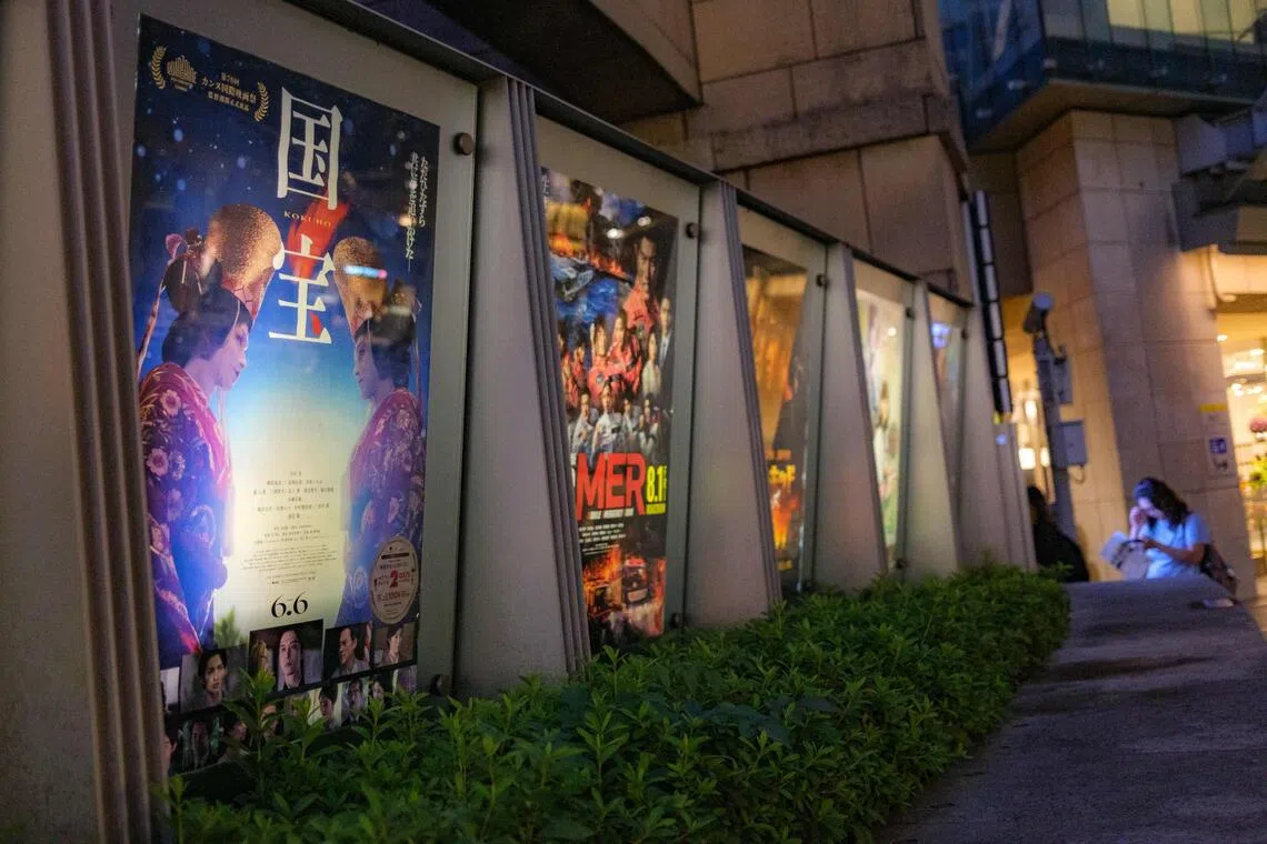 The poster of Japanese movie "Kokuho" (L) is pictured outside a cinema in Tokyo's Roppongi district on September 4, 2025. Lasting almost three hours, "Kokuho" is about two "onnagata", male players of female roles in kabuki, a rarefied form of classical Japanese theatre. Lee Sang-il's film, shot by Tunisian cinematographer Sofian El Fan, follows the friendship and rivalry of the son of a slain yakuza gangster and a boy born into a kabuki family. (Photo by Philip FONG / AFP) / To go with 'JAPAN-ANIMATION-FILM-CINEMA, FOCUS' by Natsuko FUKUE & Kyoko HASEGAWA