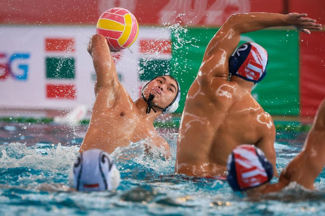 Singapore's Joshua Ong (white cap) goes up against Indonesia's water polo players in their round robin match at the SEA Games. 
