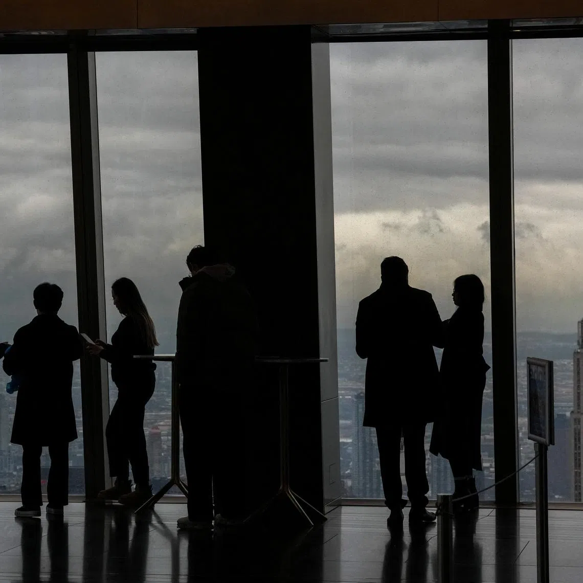 People look on as the fog clears around the Empire State building, as seen from the Edge NYC, in New York City, U.S., December 29, 2025. REUTERS/Adam Gray