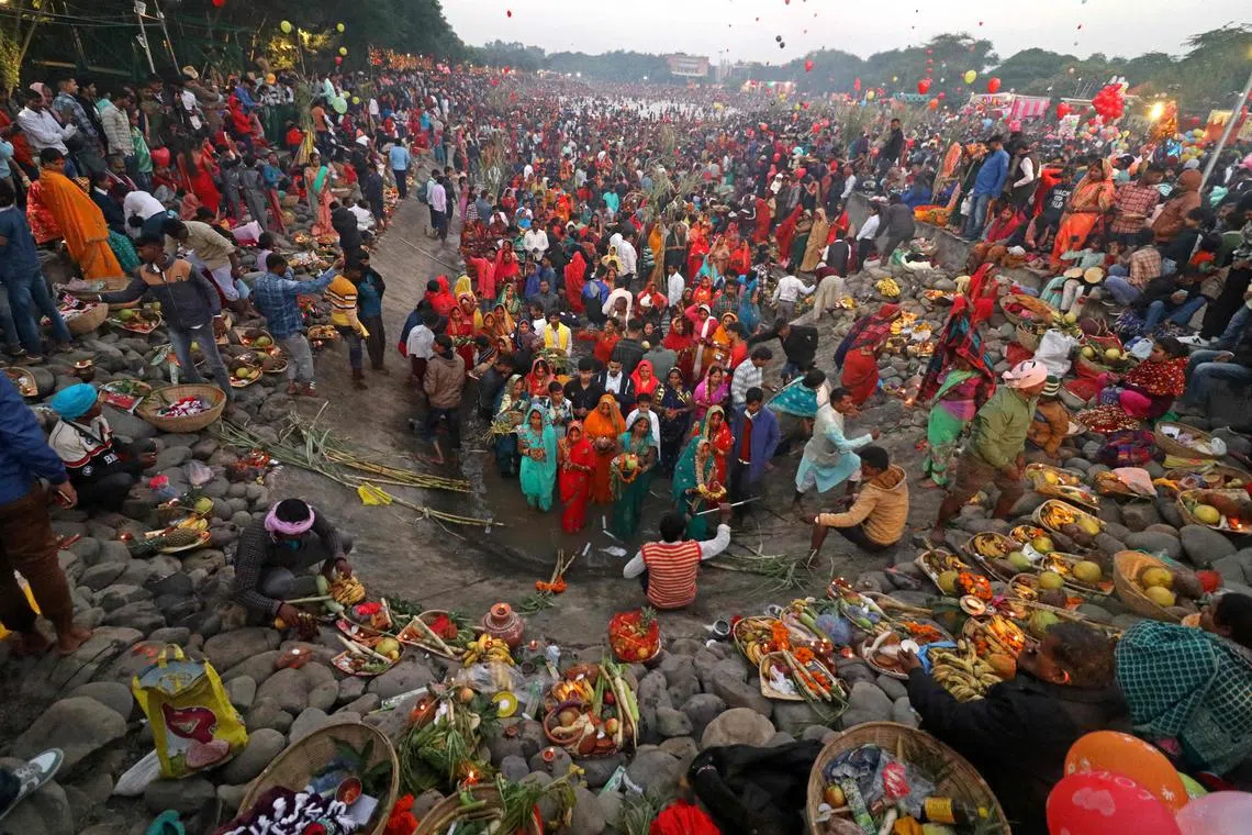 In this photograph taken on October 31, 2022, devotees take part in a ritual to worship the sun during the Hindu festival of Chhath Puja at a lake in Chandigarh. - India is projected to see an explosion in its urban population in the coming decades, but its cities already cannot cope and climate change will make living conditions harsher still. (Photo by AFP) / To go with 'India-Population-Climate-Health', FOCUS