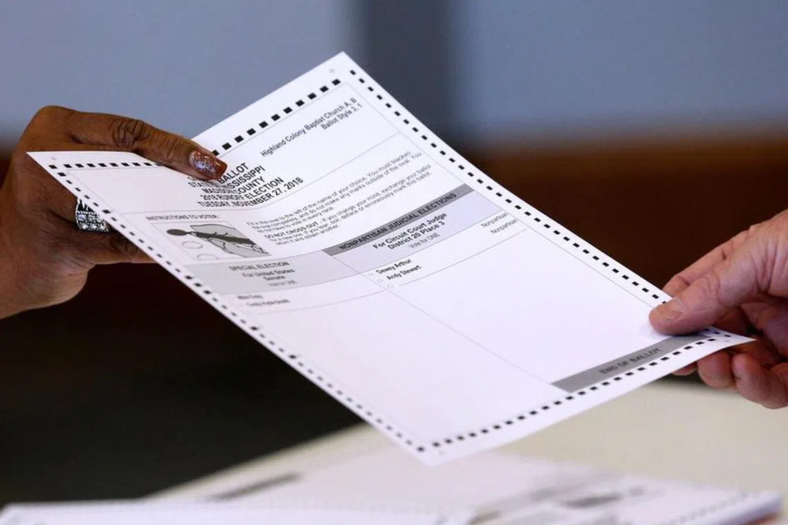 An election official hands a ballot to a voter at a polling station in Ridgeland, Mississippi, U.S., November 27, 2018. REUTERS/Jonathan Bachman/File Photo