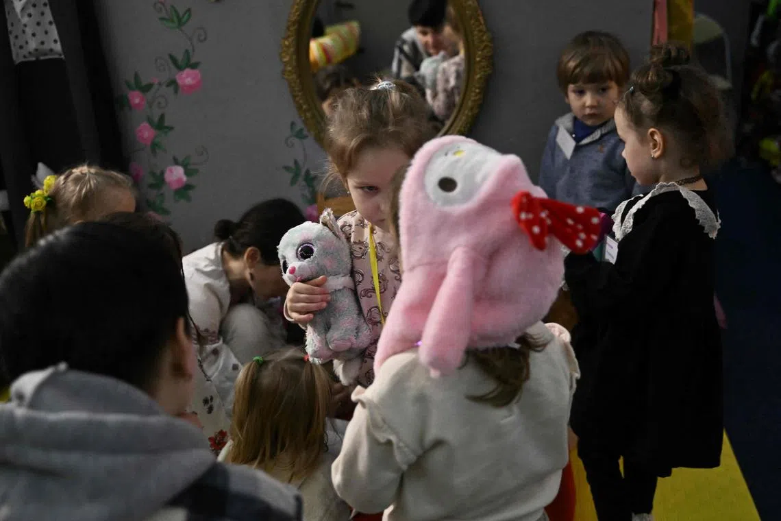 Children play in an air-raid shelter in the cellar of a kindergarten after an alarm signal in Kyiv on March 20, 2023, amid the Russian invasion of Ukraine. In the cellar of a Kyiv kindergarten decorated with bunting and wall paintings of doughnuts and cats, dozens of children are taking shelter during an air raid. 
