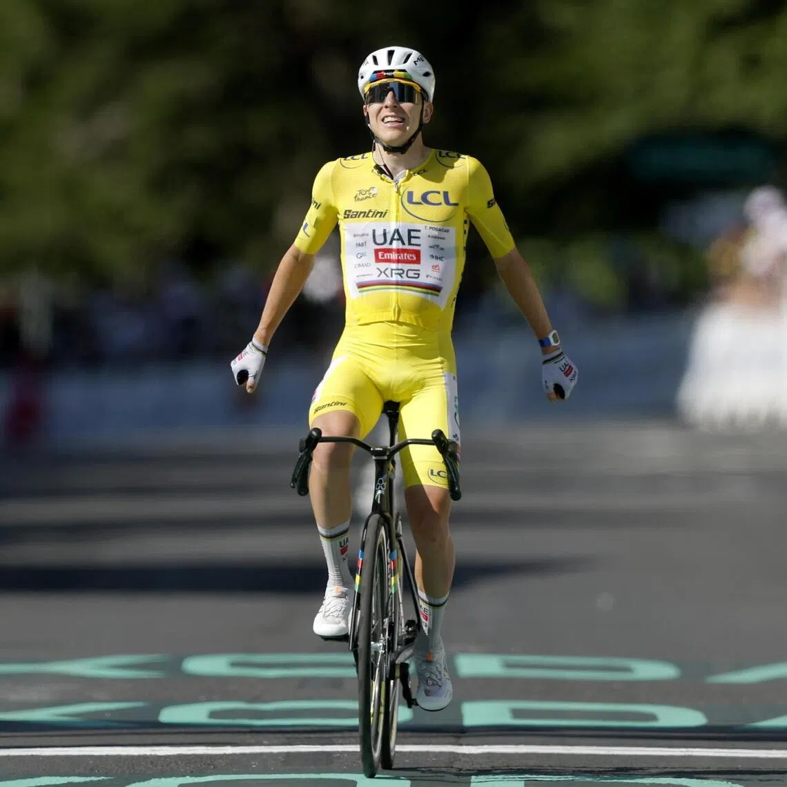 Slovenian cyclist Tadej Pogacar, of UAE Team Emirates XRG, celebrates as he crosses the finish line to win Stage 10 of the Tour de France.