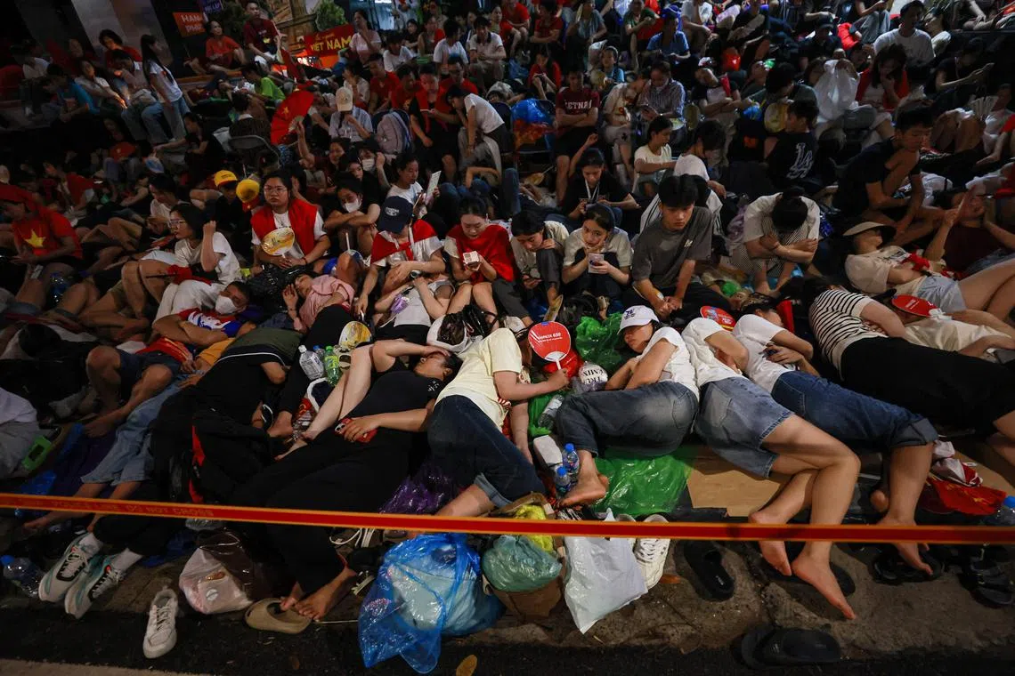 People waiting overnight, sleep and sit along a road to reserve their spot in Hanoi in the early hours of September 2, 2025 ahead of a parade marking Vietnams 80th National Day celebrations.