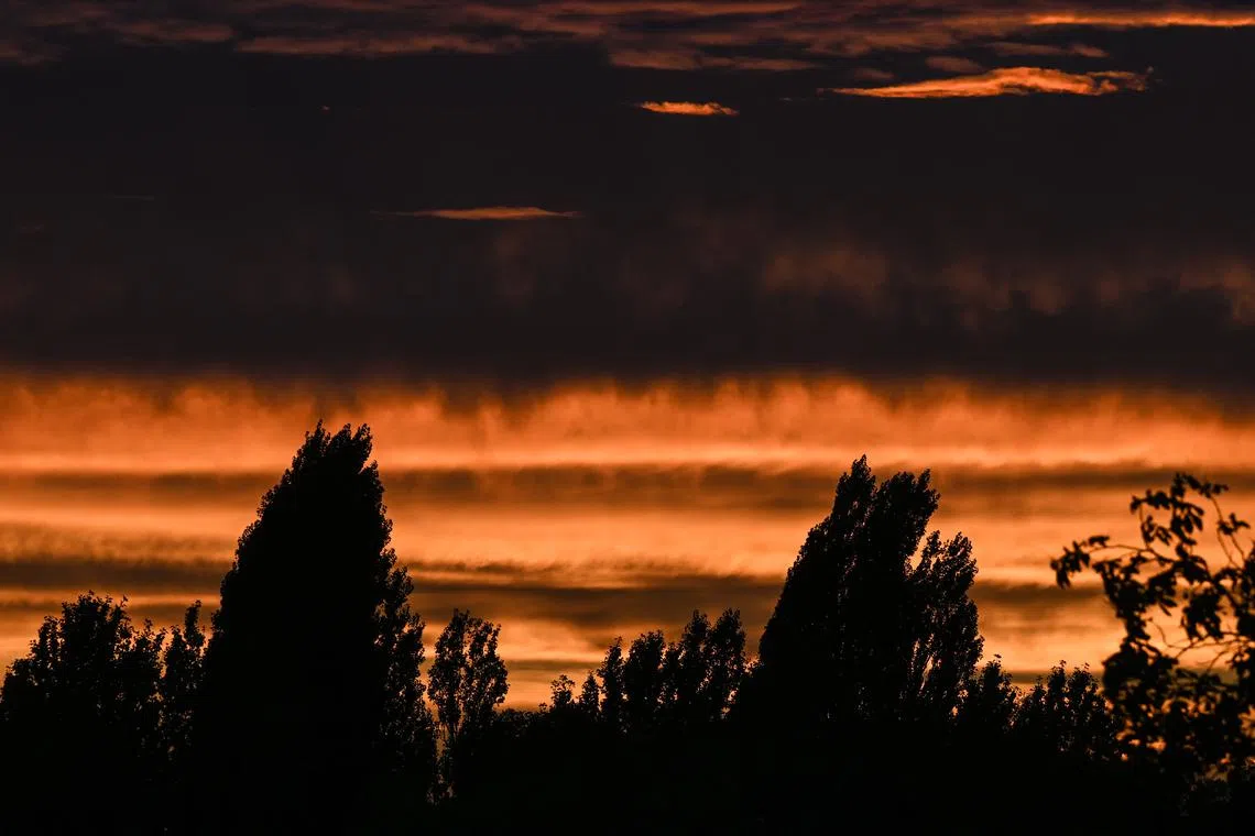The setting sun creating a dramatic illumination of the clouds in the evening sky over trees in Berlin, Germany on Sept. 18