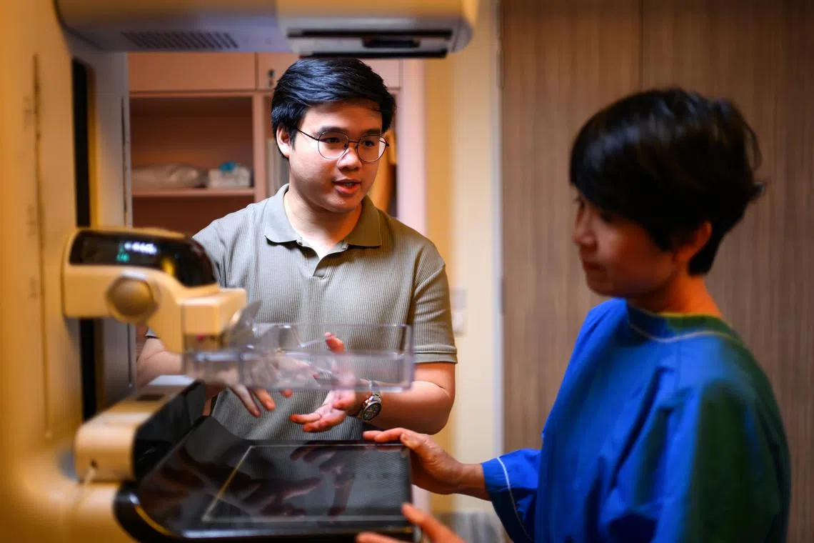 Singapore winner of the 2024 James Dyson Award, Luke Goh, showing his mum Jessica Chua how his invention can improve one's mammogram experience.