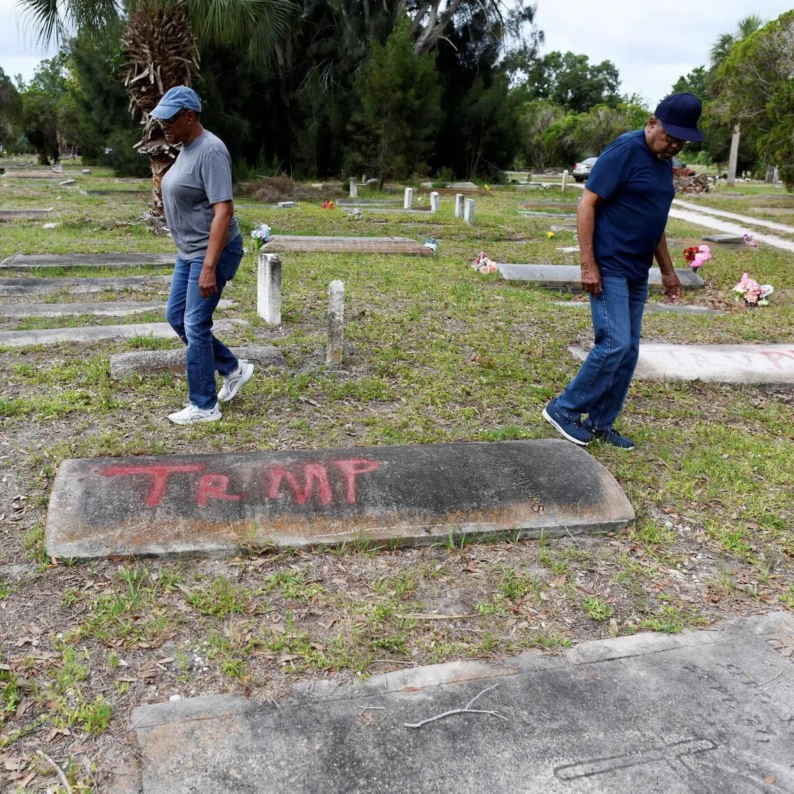 Family members of those buried at the Old Memphis Cemetery, a predominantly African-American cemetery in Palmetto, Florida, walking near a tomb with the word "Trump" spray-painted on it on May 14.