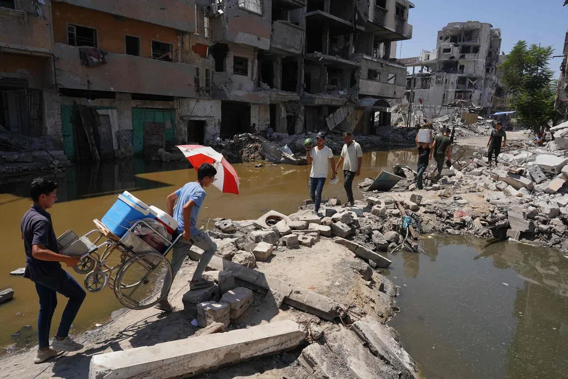 Palestinians walk on the rubble of buildings destroyed in previous Israeli bombardment in Khan Yunis in the southern Gaza Strip, on July 19, 2024.