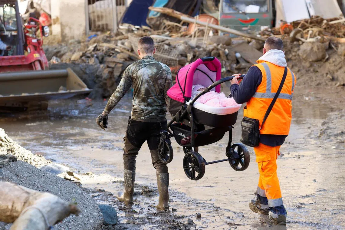 Men carry a stroller with a baby following a landslide on the Italian holiday island of Ischia, Italy, Nov 27, 2022. 