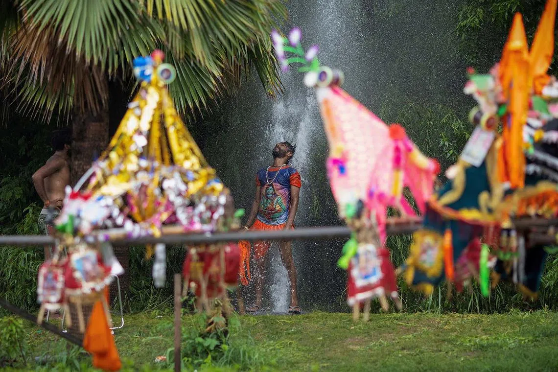 A Hindu devotee bathing next to the containers filled with the water from the river Ganges - an offering to Lord Shiva for the betterment of their families and society - in New Delhi, India, July 22, 2025. 