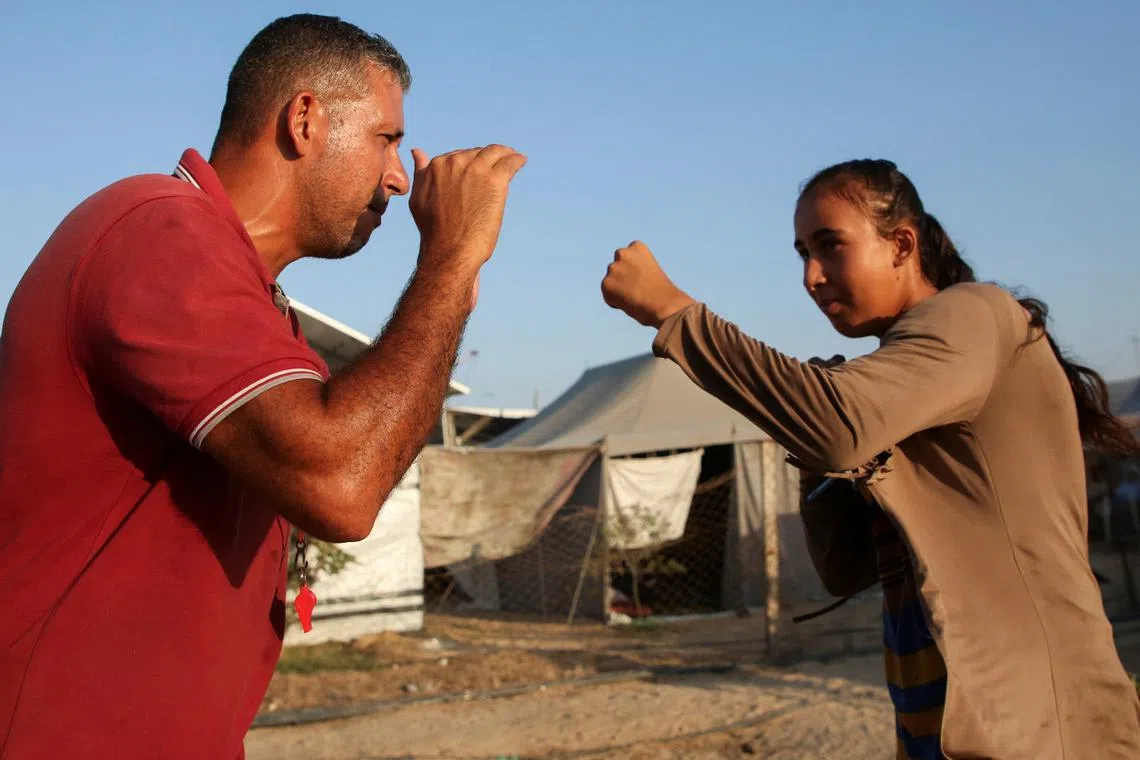 FILE PHOTO: Palestinian boxing coach Osama Ayoub trains girls on boxing near a tent camp sheltering displaced people, amid Israel-Hamas conflict, in Khan Younis in the southern Gaza Strip July 10, 2024. REUTERS/Hatem Khaled/File Photo