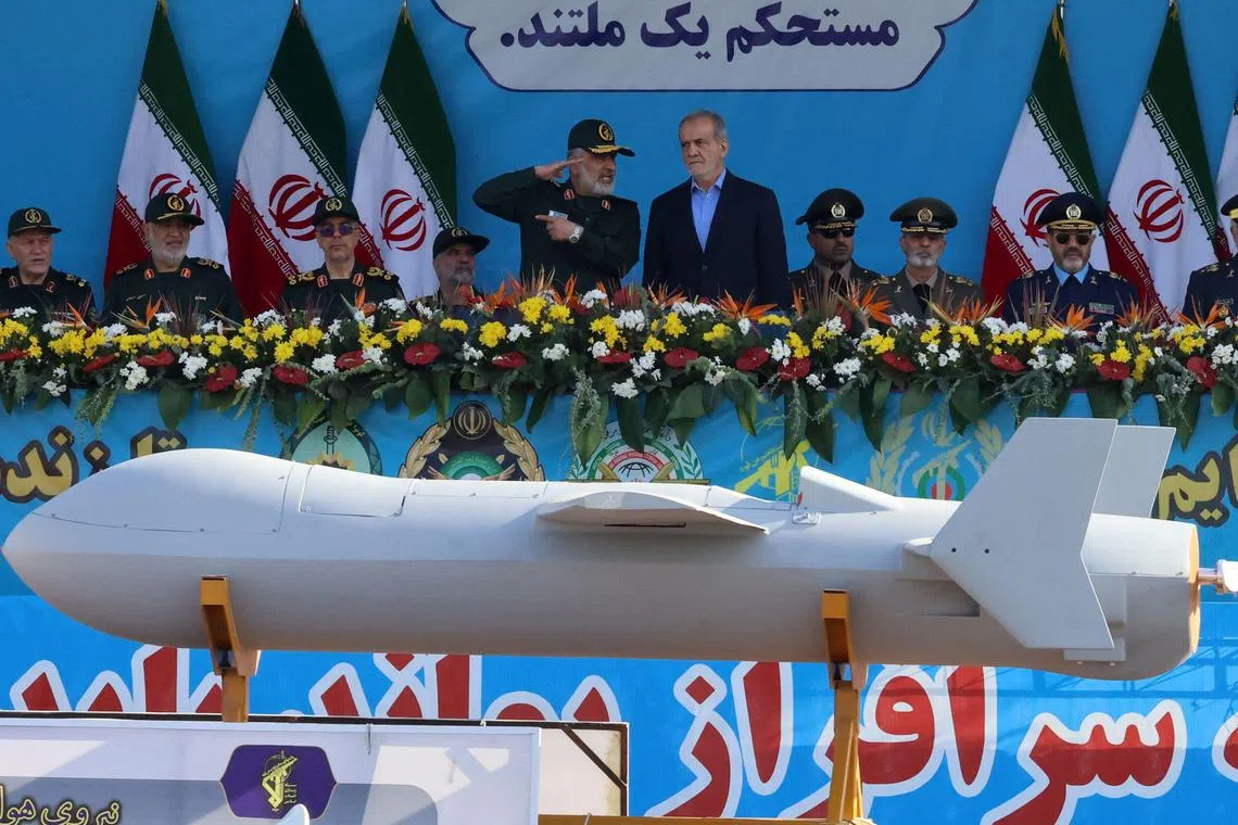 Iranian President Masoud Pezeshkian (R) and commander of the Islamic Revolutionary Guard Corps' Aerospace Force Amir Ali Hajizadeh look on as Iran's new Shahed 136-B drone is displayed during the annual military parade marking the anniversary of the outbreak of the 1980-1988 war with Saddam Hussein's Iraq, in Tehran on September 21, 2024. (Photo by ATTA KENARE / AFP)
