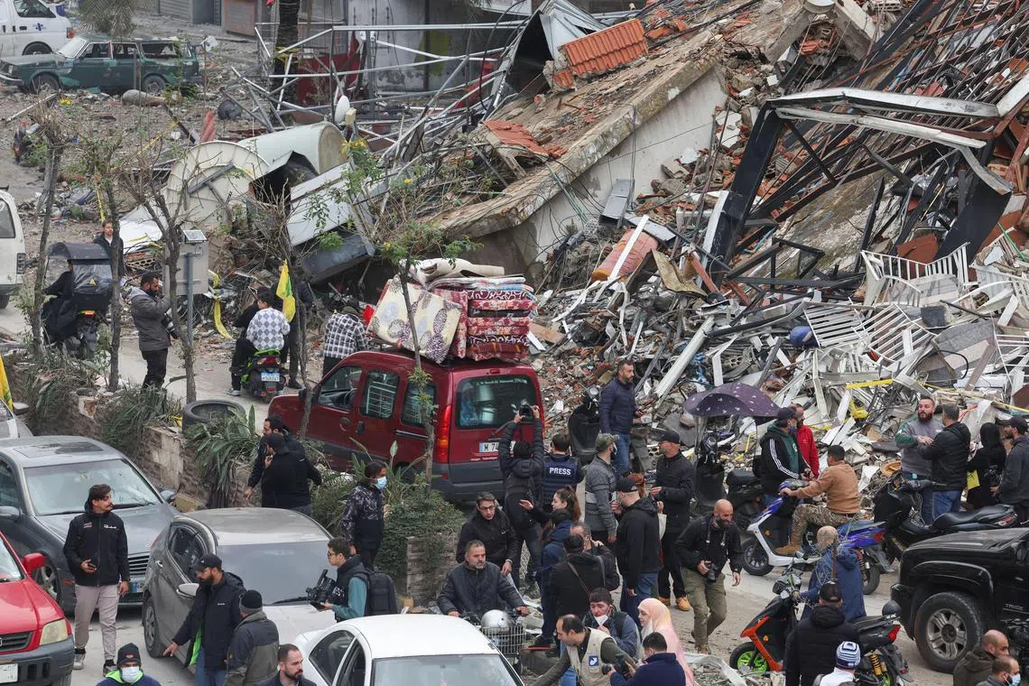 People gather as cars drive past rubble in Beirut after a ceasefire between Israel and Hezbollah took effect on Nov 27.