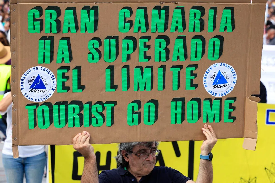 A man displays a sign that reads \"Gran Canaria has exceeded the limit\", during a demonstration calling for a change in the tourism model in the Canary Islands, in Las Palmas de Gran Canaria, Spain, May 18, 2025. REUTERS/Borja Suarez