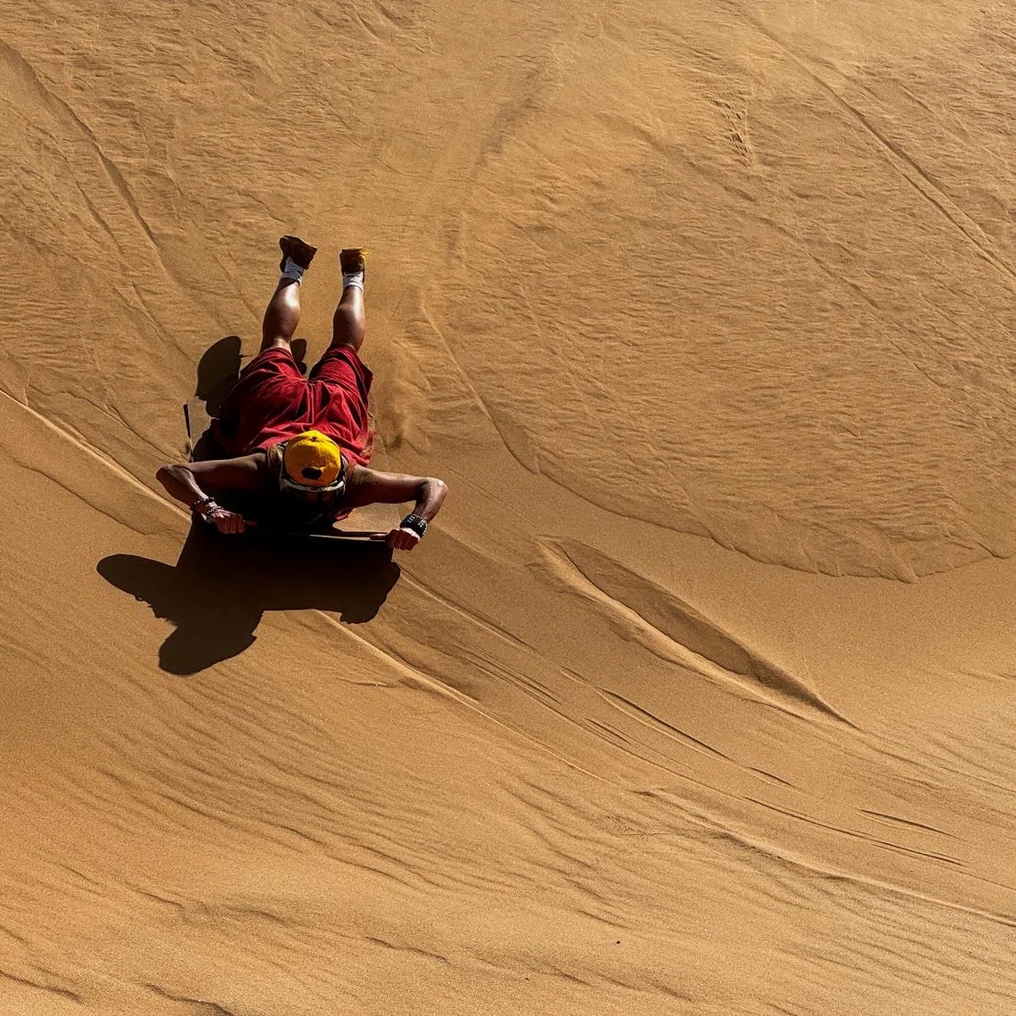 A tourist sandboards on the dunes in Walvis Bay, Namibia February 26, 2024. REUTERS/Shafiek Tassiem