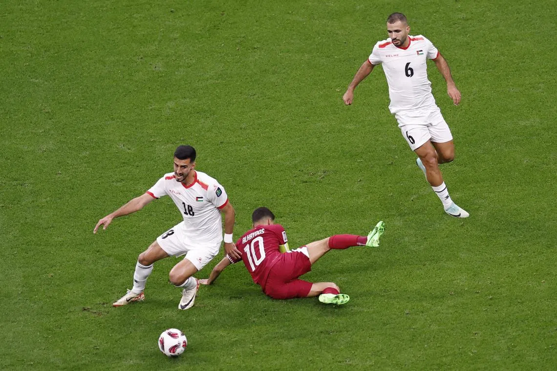 Qatar's Hassan Al-Haydos in action with Palestine's Ameed Mahajna and Odai Kharoub.