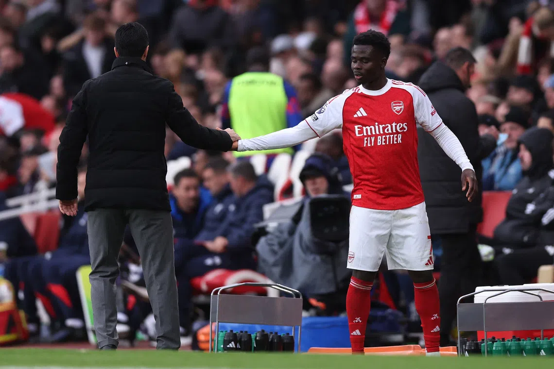 Soccer Football - Premier League - Arsenal v Crystal Palace - Emirates Stadium, London, Britain - October 26, 2025 Arsenal's Bukayo Saka shakes hands with Arsenal manager Mikel Arteta after being substituted REUTERS/David Klein