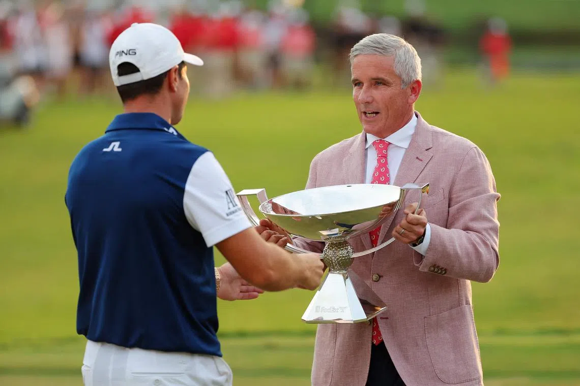 PGA Tour Commissioner Jay Monahan presents Viktor Hovland of Norway with the Tour Championship trophy.