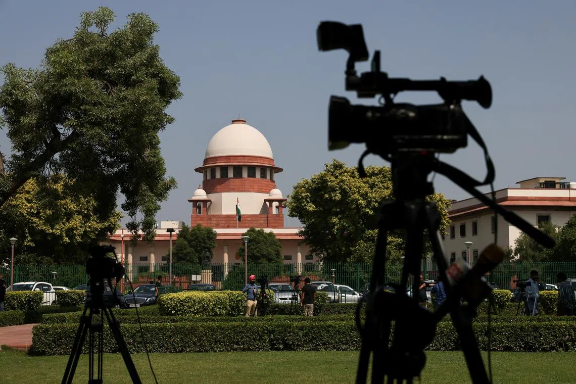 FILE PHOTO: Members of media speak in front of cameras after a panel of the Supreme Court said it was divided on a decision to allow hijabs in classrooms, outside the premises of the court in New Delhi, India October 13, 2022. REUTERS/Anushree Fadnavis/File Photo