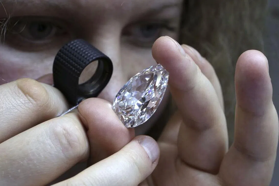 An employee inspects a diamond during a demonstration at the lapidary enterprise \"Diamonds ALROSA\", owned by Alrosa company, in Moscow, October 17, 2013.  REUTERS/Sergei Karpukhin/ File Photo