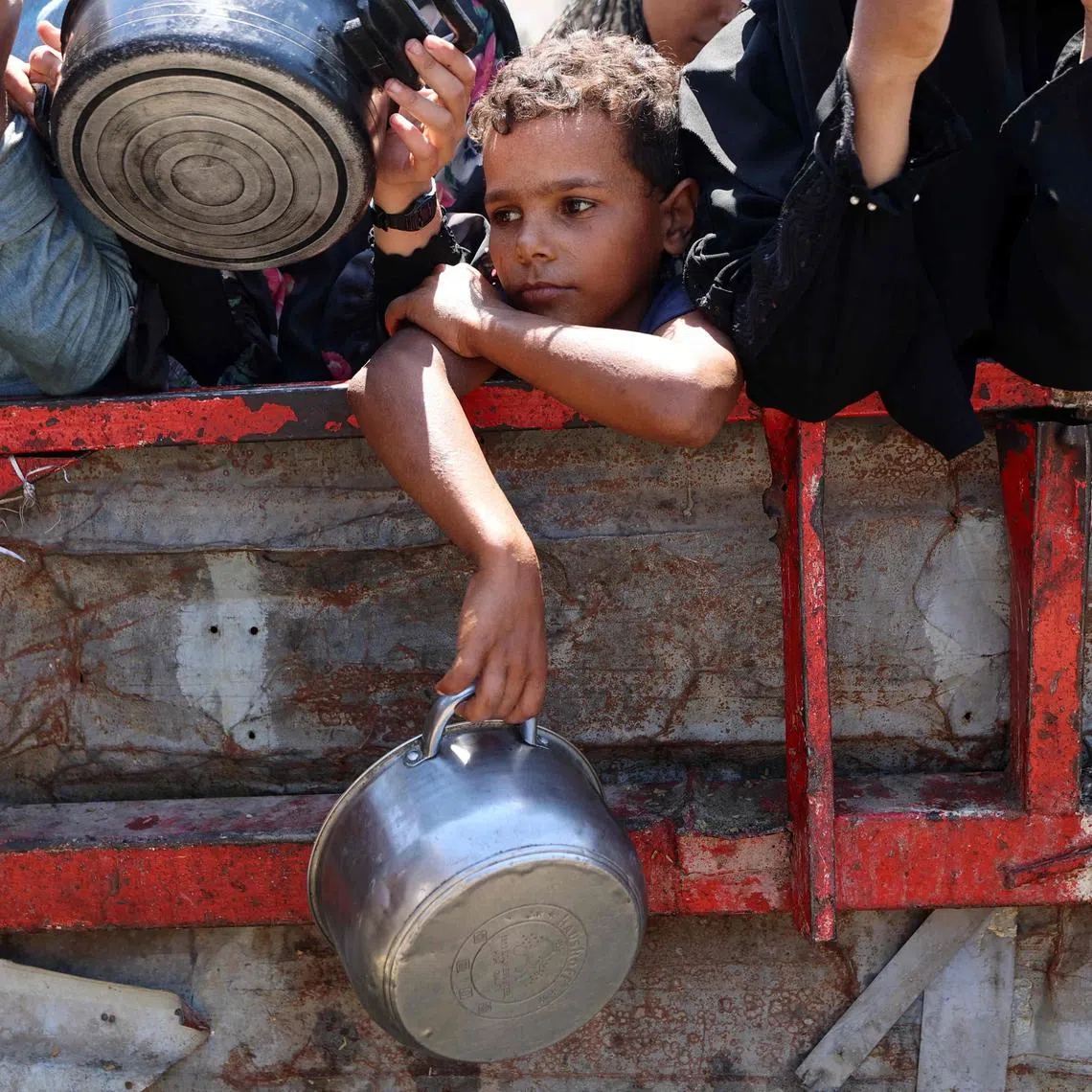 A Palestinian boy holding an empty pot as he waits with others to receive cooked rice at a charity kitchen in Gaza City on Aug 23.