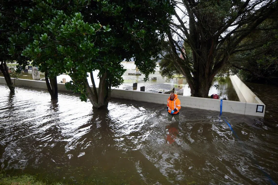 A worker walks in floodwaters following Cyclone Gabrielle in Auckland, New Zealand, Feb 14, 2023. 