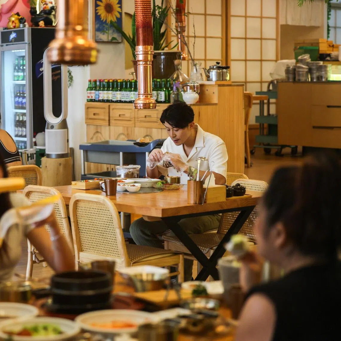 A member of staff pose as a solo diner at Hansik Dining Collective. The restaurant offers smaller portions of food for diners eating alone. Photographed at Hansik Dining Collective on Apr 10, 2026.