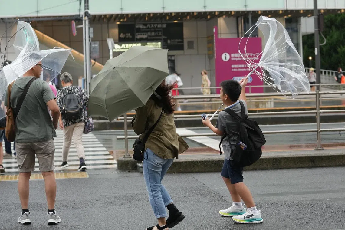 Pedestrians struggling against strong wind in Tokyo on Aug 16 as typhoon Ampil approaches.