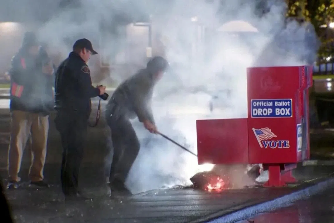 First responders pull out the burning contents of a ballot box, used to collect early votes ahead of the Nov 5 US election, after it was set on fire in a suspected arson in Vancouver, Washington on Oct 28.
