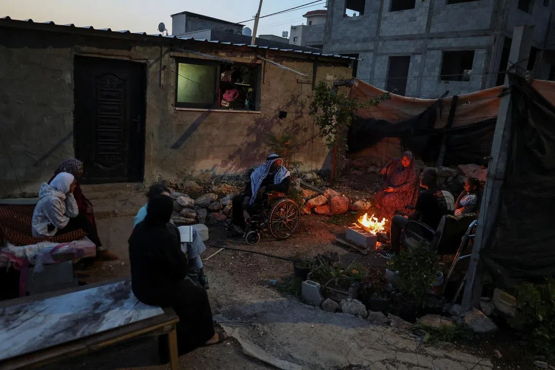 The Ghanem family sit around a fire outside a shack near Tulkarm in the Israeli‑occupied West Bank, February 16, 2026. Members of the family were displaced last year from the Tulkarm refugee camp. REUTERS/Ammar Awad  SEARCH "AWAD TULKAREM" FOR THIS STORY. SEARCH "WIDER IMAGE" FOR ALL STORIES.