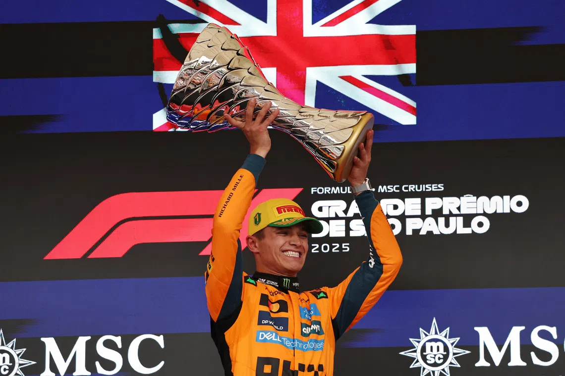 McLaren's Lando Norris celebrates on the podium with a trophy after winning the Sao Paulo Grand Prix.