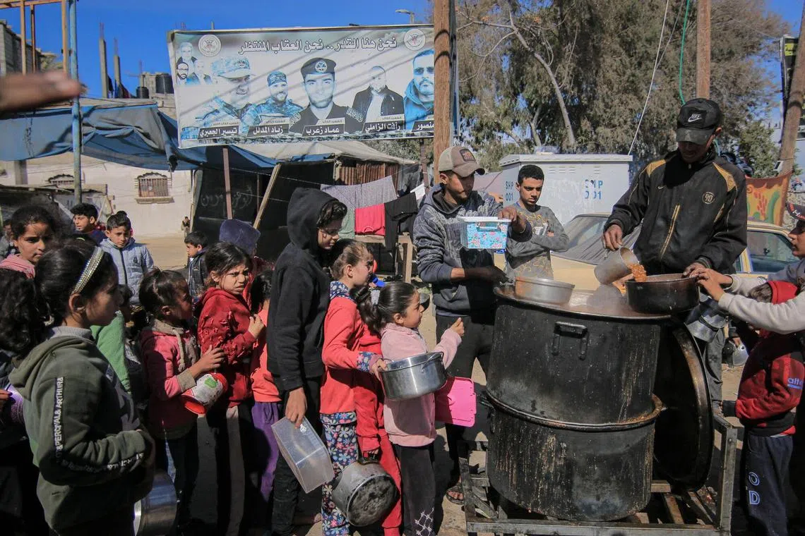 Displaced Palestinians collect free food from a street kitchen in the west of Rafah, Gaza Strip, on Thursday. Feb. 1, 2024. Negotiations are advancing for an agreement to pause the Israel-Hamas war and free civilian hostages captured by Hamas, people familiar with the matter said. Photographer: Ahmad Salem/Bloomberg