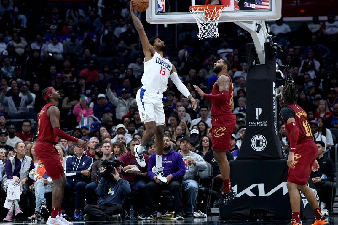 Paul George of the Los Angeles Clippers dunking in front of Caris LeVert (No. 3), Marcus Morris Sr. (No. 24), and Darius Garland of the Cleveland Cavaliers during a 120-118 Clippers NBA win at Crypto.com Arena on April 07.