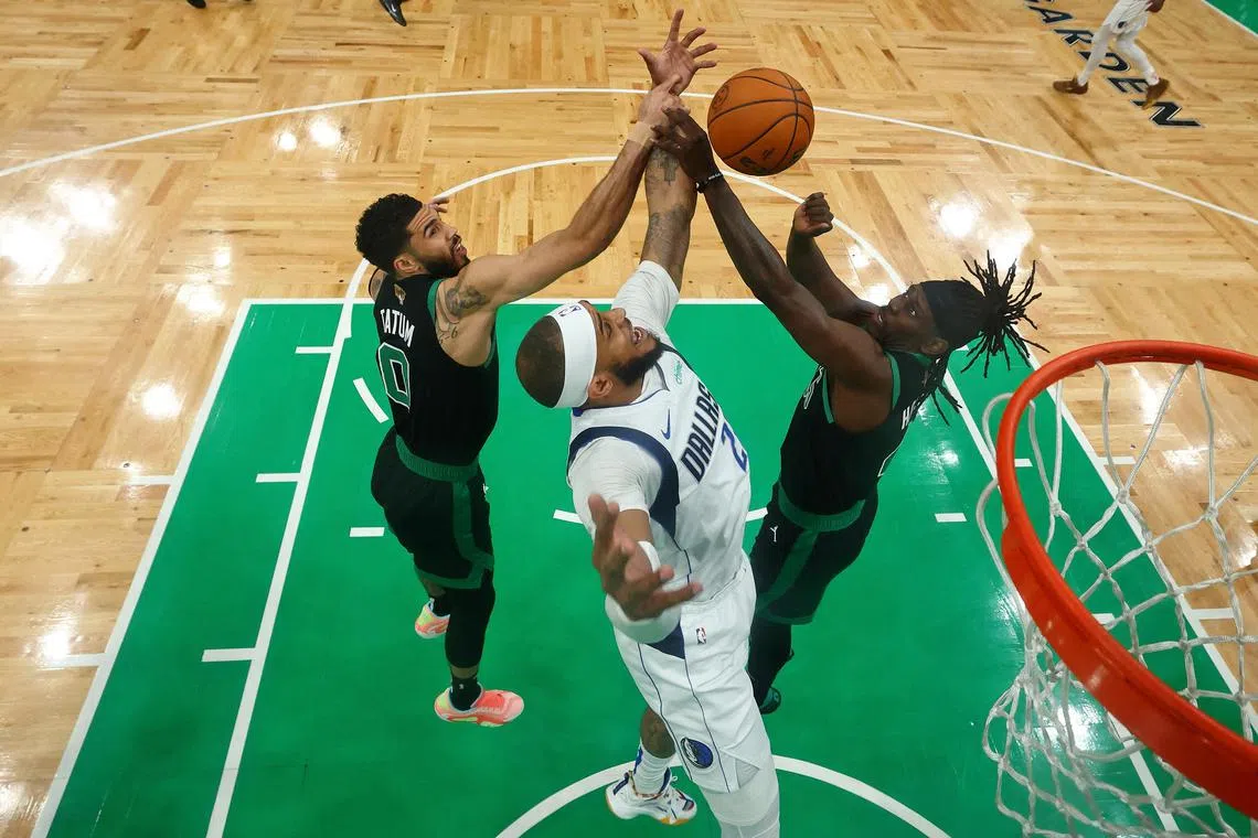 Dallas Mavericks centere Daniel Gafford (No. 21) reaching for the ball against Boston Celtics forward Jayson Tatum (left) and guard Jrue Holiday during the NBA Finals at TD Garden.