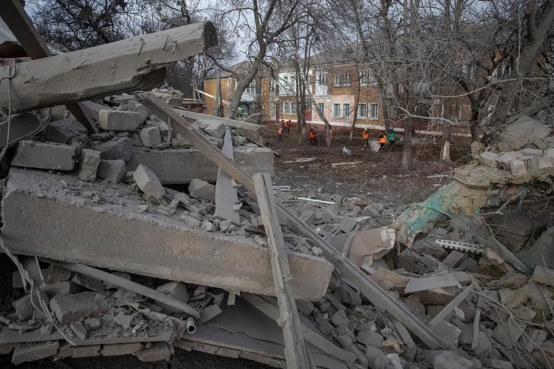 A file photo shows communal workers cleaning an area near a school building destroyed by a Russian military strike, in Kramatorsk, Ukraine, on Dec 23, 2022.