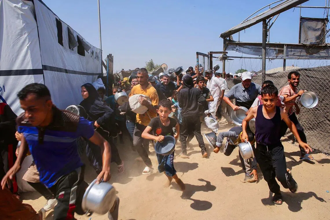 Palestinian children making a dash for a meal at a charity kitchen in the Mawasi area of Khan Yunis in the southern Gaza Strip on July 22, 2025. 
