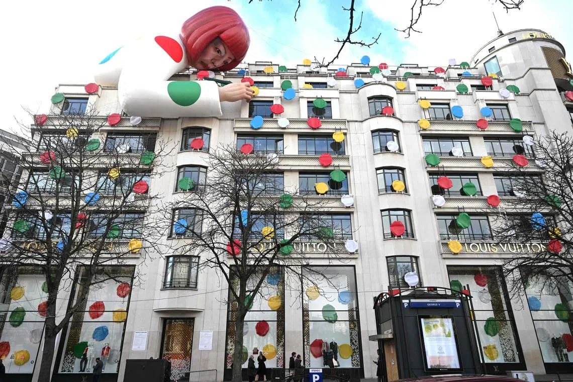 This photo taken on January 13, 2023, shows a large blow up doll depicting Japanese contemporary artists Yayoi Kusama decorating the French luxury brand Louis Vuitton flagship store on the Champs-Elysees avenue in Paris. (Photo by Emmanuel DUNAND / AFP)