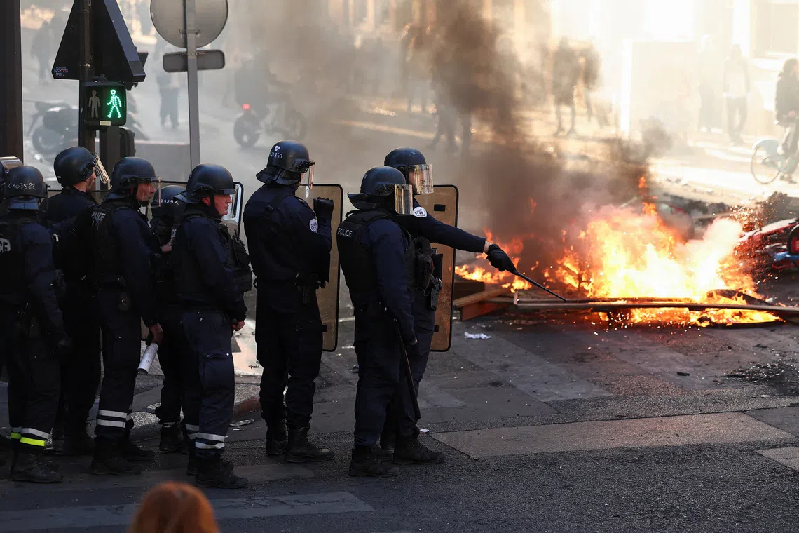 Police officers in riot gear stand near burning fire, in Paris, France, October 18, 2026. REUTERS/Abdul Saboor