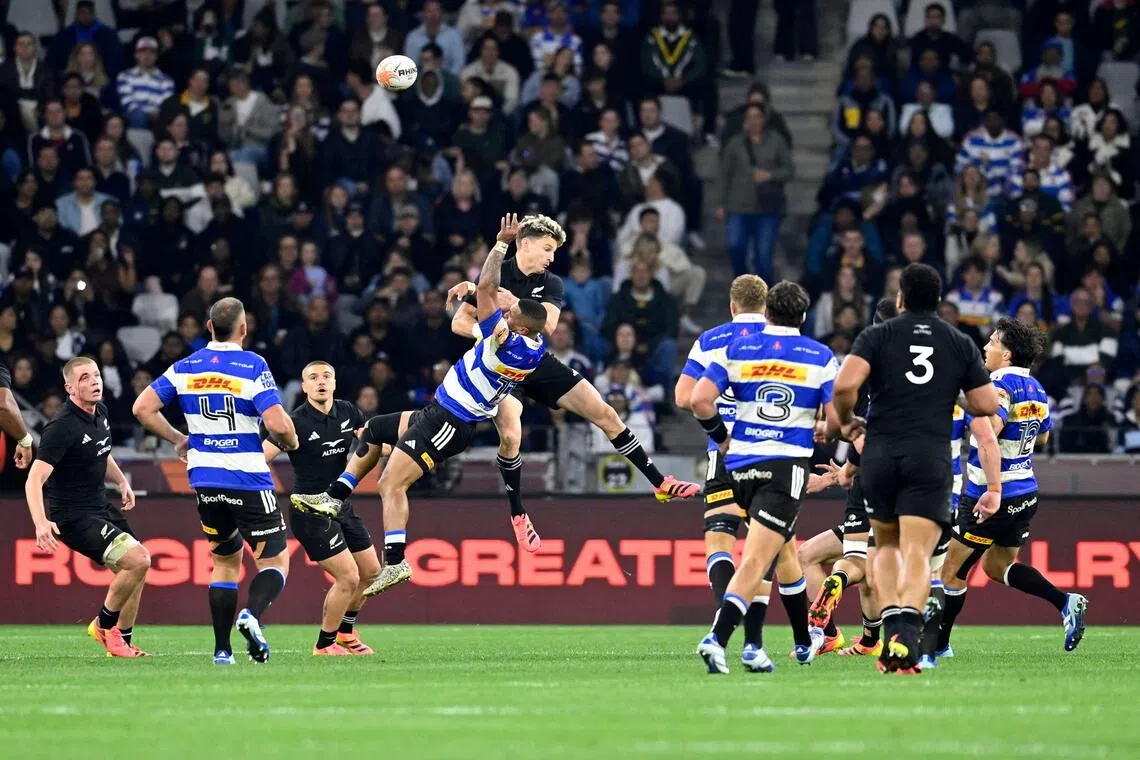Stormers’ wing Leolin Zas leaps with New Zealand’s fly-half Beauden Barrett during a rugby union tour match at the Cape Town Stadium on Aug 7.