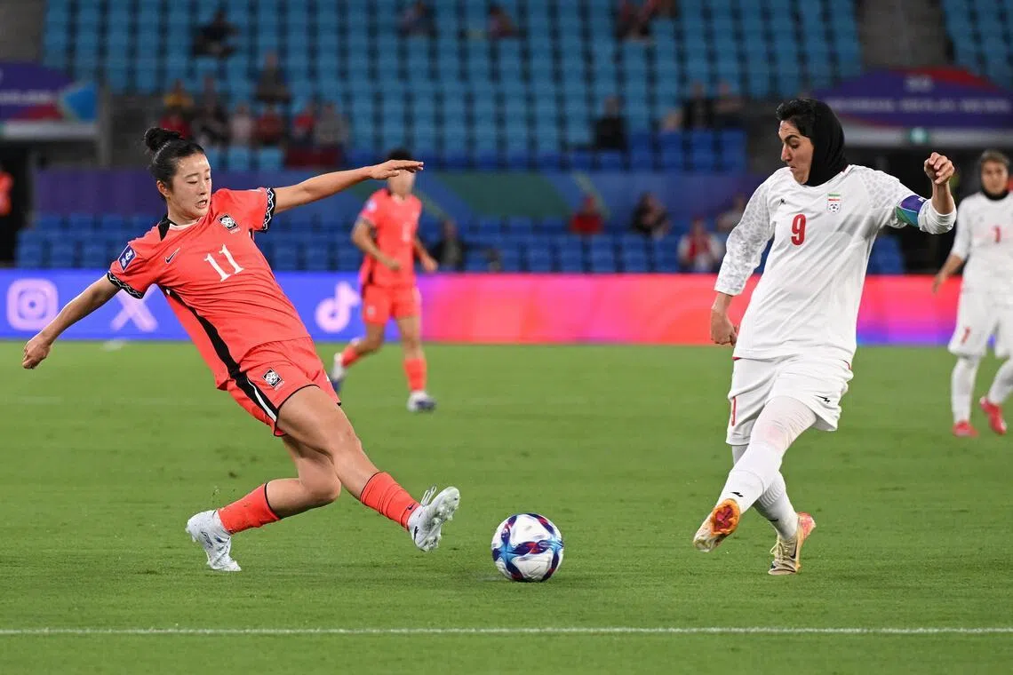 Choe Yu-ri of South Korea competes with Zahra Ghanbari of Iran during their Women's Asian Cup match.