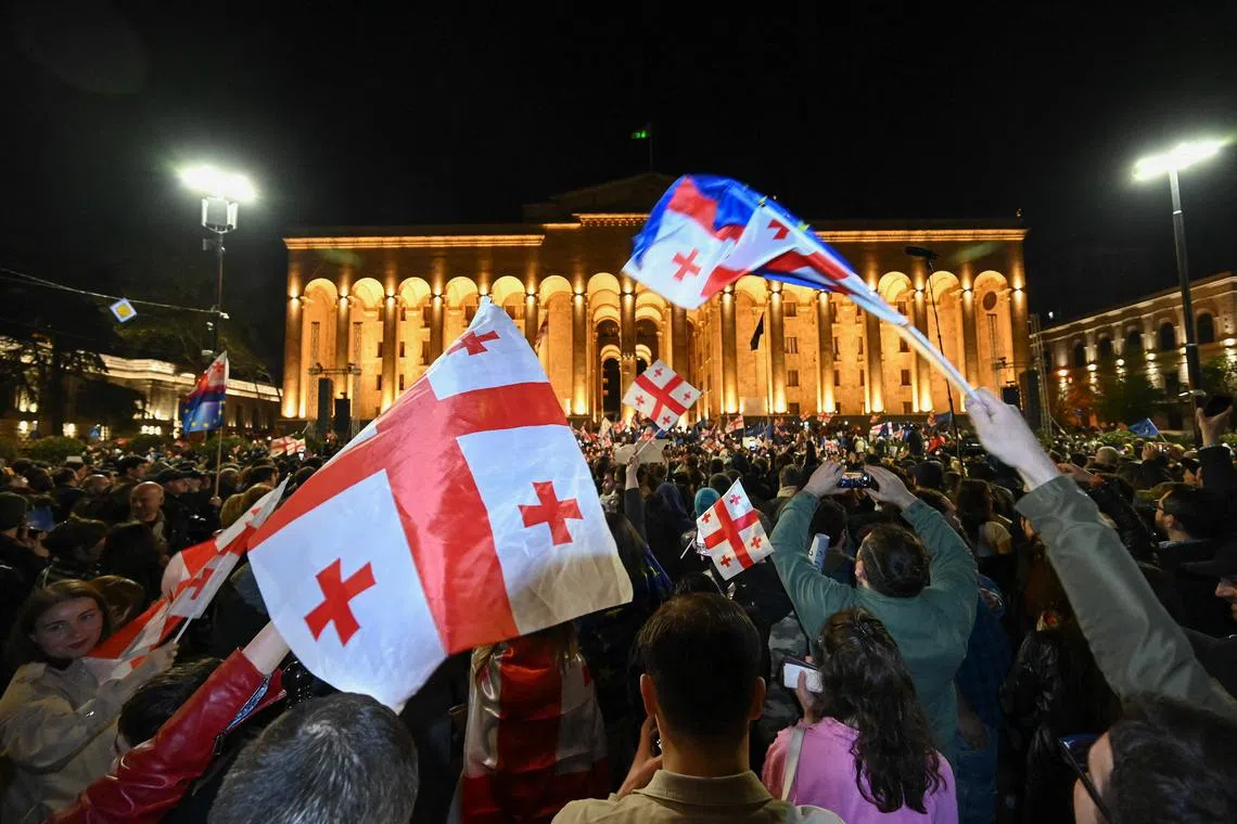 Pro-democracy activists wave Georgian flags, as they protest against a repressive "foreign influence" Bill outside the parliament in Tbilisi.