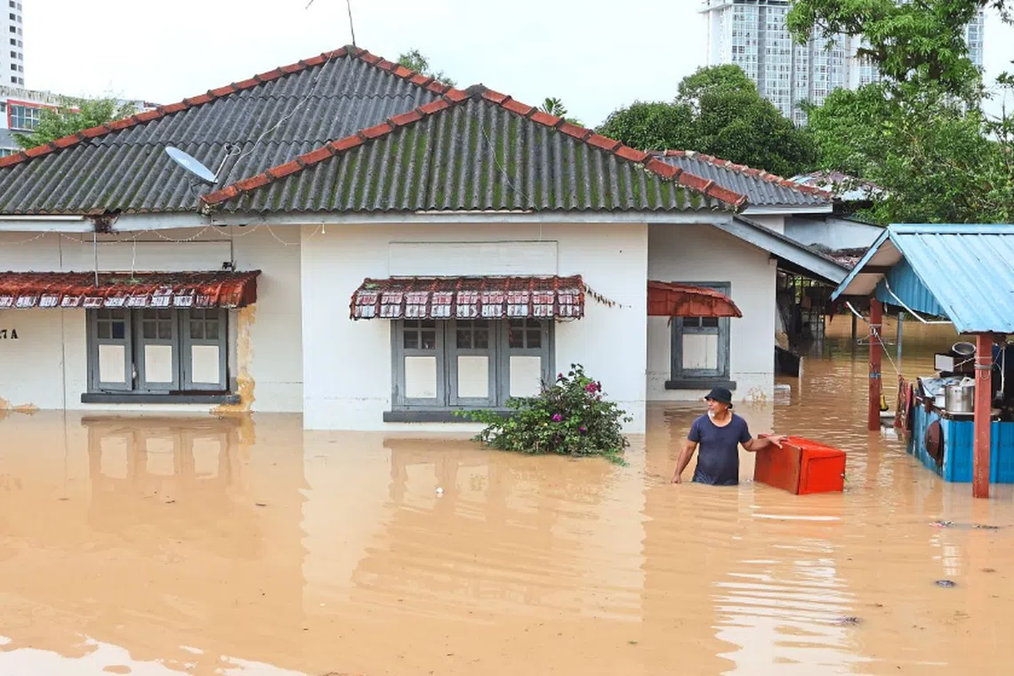 A man standing in waist-high water outside his house in Kampung Mohd Amin after a flash flood due to a two-hour thunderstorm.