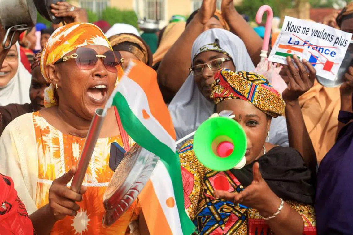 FILE PHOTO: A person holds a paper that reads &#039;We no longer want France&#039; as Nigerien women demonstrate by hitting and carrying kitchen utensils in support of the putschists in front of French Army headquarters, in Niamey, Niger August 30, 2023. REUTERS/Mahamadou Hamidou /File Photo