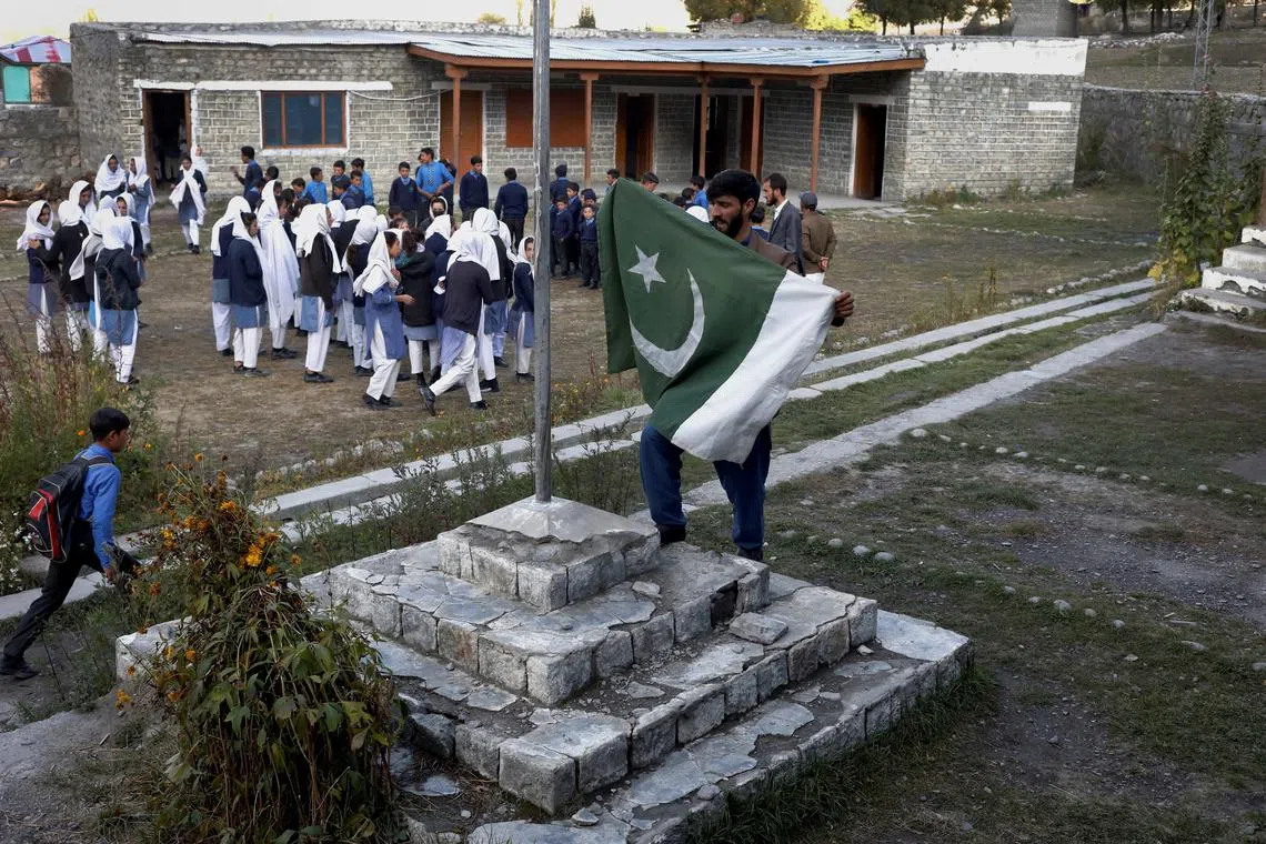 A man preparing to hoist the national flag as students gather for the morning assembly at Govt. Middle School, in Darkut village, Yasin valley, in the Gilgit-Baltistan region of Pakistan, Oct 13, 2023. 