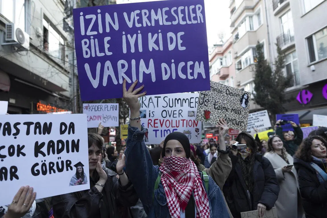 People hold placards saying 'Even if they don't let me, I will say I am glad I exist' and shout slogans during a demonstration marking International Women's Day in Istanbul on March 8. 
