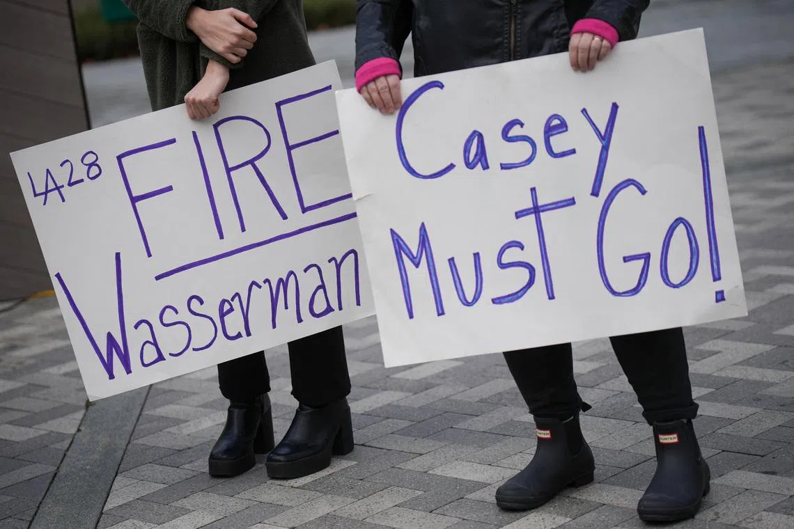 People hold placards on the day local elected officials, survivors and activists hold a press conference calling for the removal of Casey Wasserman as head of the LA Olympic Committee following revelations of his ties to Ghislaine Maxwell, in Los Angeles, California, U.S., February 17, 2026. REUTERS/Daniel Cole