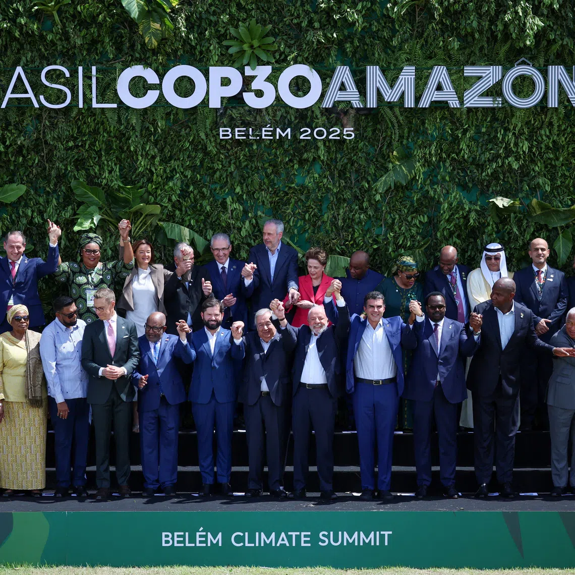 Brazil's President Luiz Inacio Lula da Silva, United Nations Secretary-General Antonio Guterres and other delegates attending the Belem Climate Summit ahead of the United Nations Climate Change Conference (COP30) raise hands as they pose for a family photo, in Belem, Brazil, November 7, 2025. REUTERS/Adriano Machado