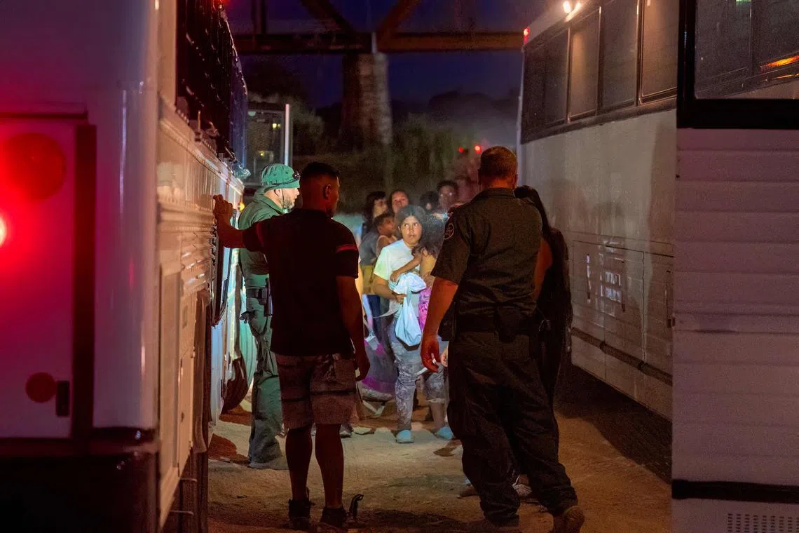 Border Patrol agents escort migrants onto a bus to be taken to a processing facility to begin their asylum-seeking process in Eagle Pass, Texas, on June 25.